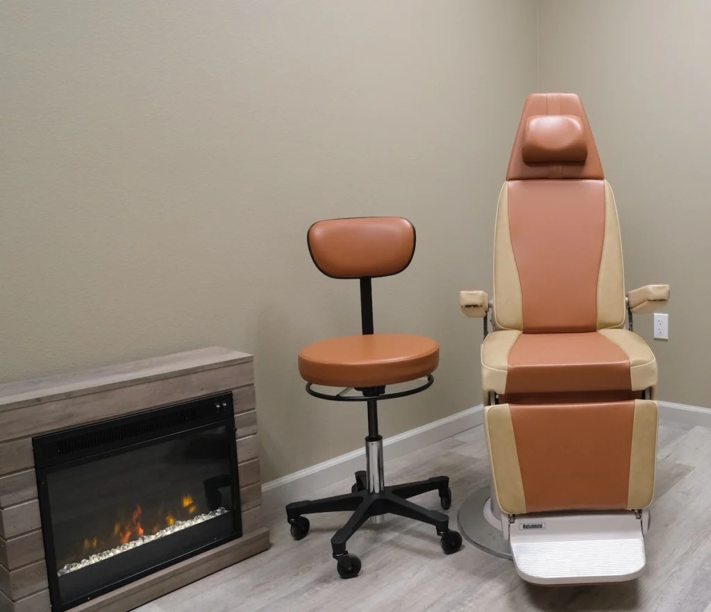 Cozy exam room with comfortable specialty procedure chair with soft earth tone upholstery and electric fireplace
