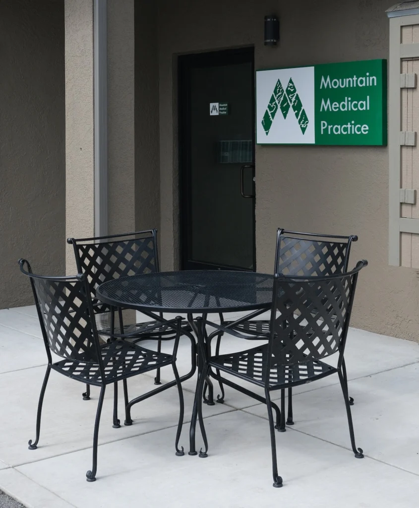 Outdoor patio table and chair set in black mesh and wrought iron style in front of Mountain Medical Practice