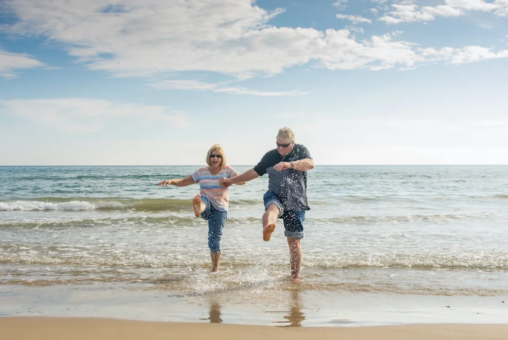 Senior couple cheerfully marching on the beach at the shorebreak