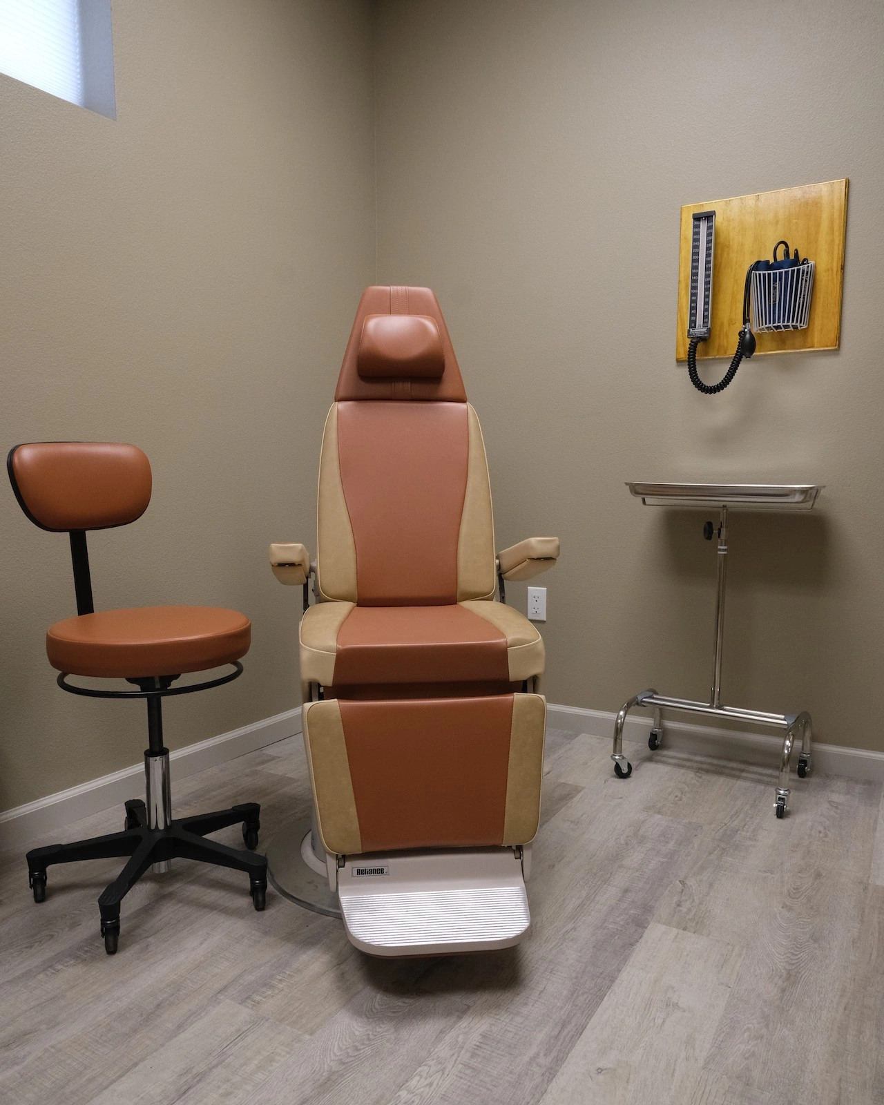 Cozy exam room with stylish specialty procedure chair in warm earth tones of sienna and tan soft upholstery by Haag-Streit Reliance surrounded by rustic lodge style accents