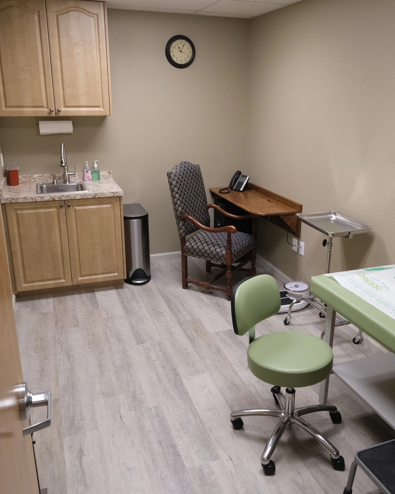 Cozy exam room with orthopedic type exam table in light green vinyl upholstery surrounded by rustic lodge style accents