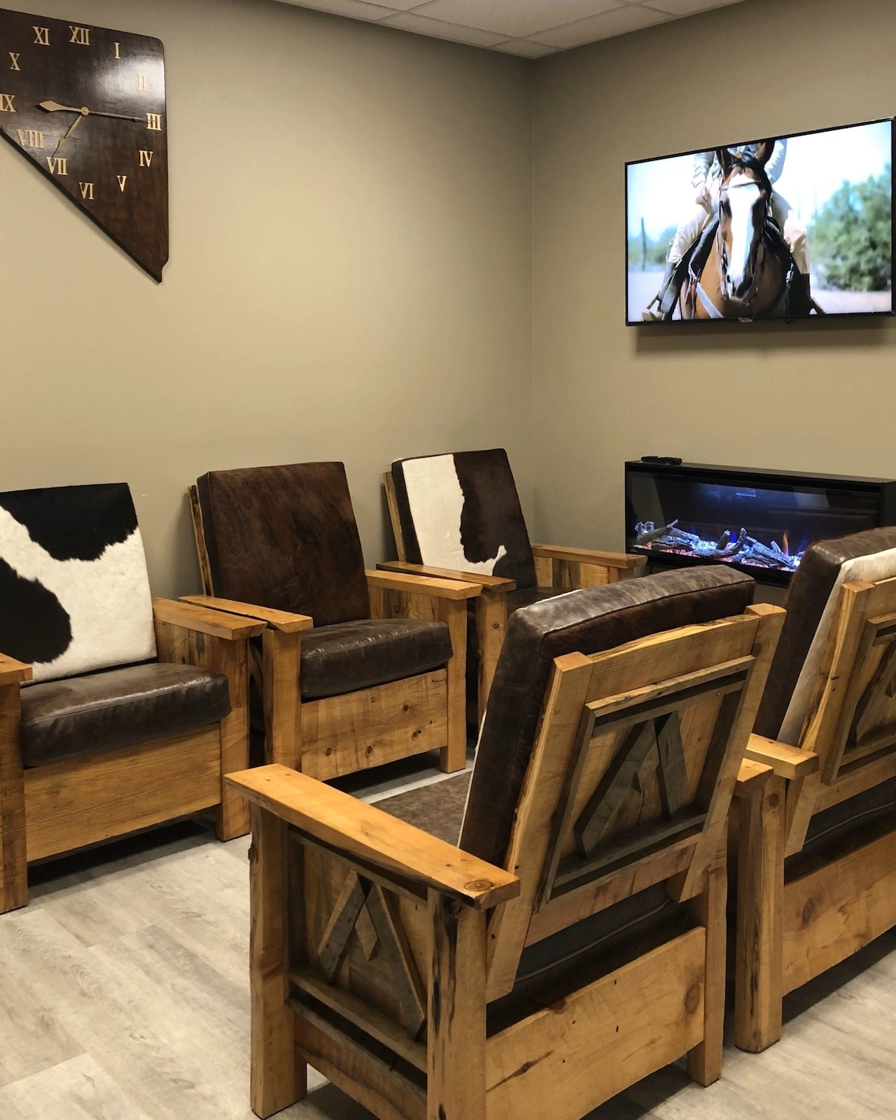 Mountain Medical Practice waiting room with rugged elegant ambience with custom-made Adirondack style cowhide upholstered chairs, electric fireplace, large screen television, and large nostalgic wall clock shaped like the State of Nevada