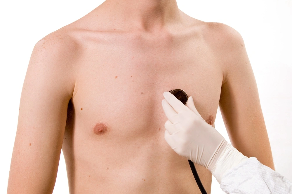 Female healthcare provider placing stethoscope on the chest of a young male patient