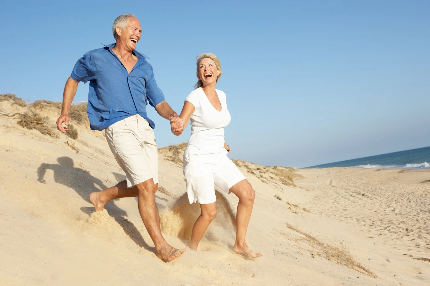 Happy healthy senior couple running on the beach