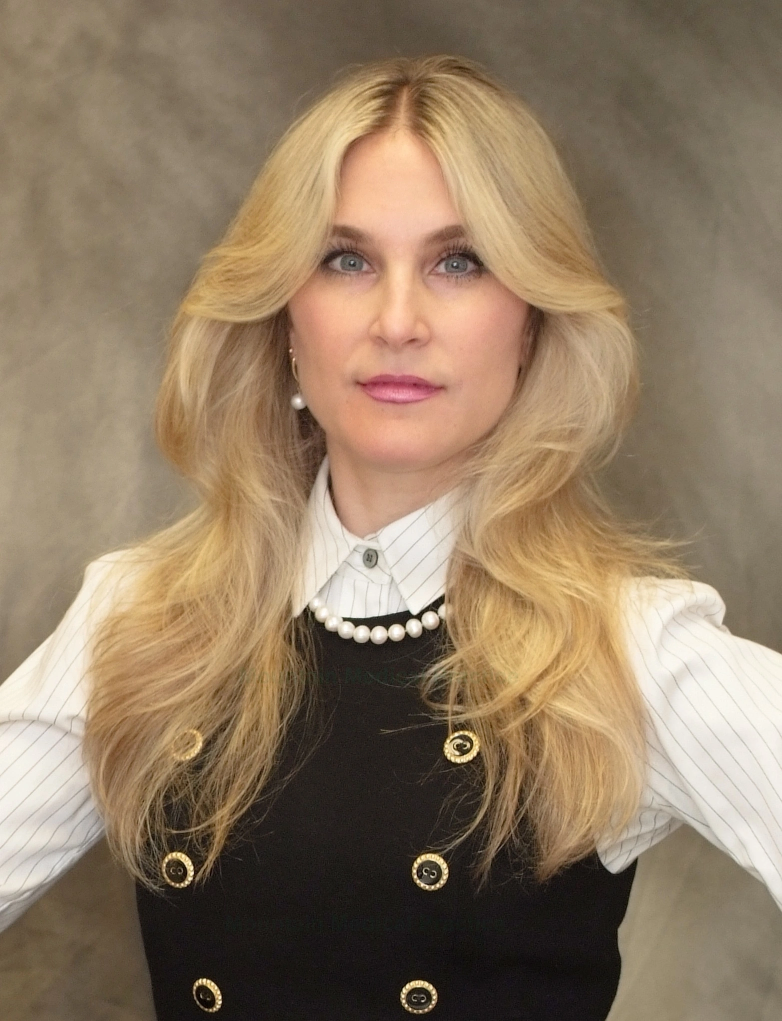 Maria Pirraglia in white shirt with gray pinstripes, black double-breasted wool crepe jumper, and white pearl necklace, facing straight on