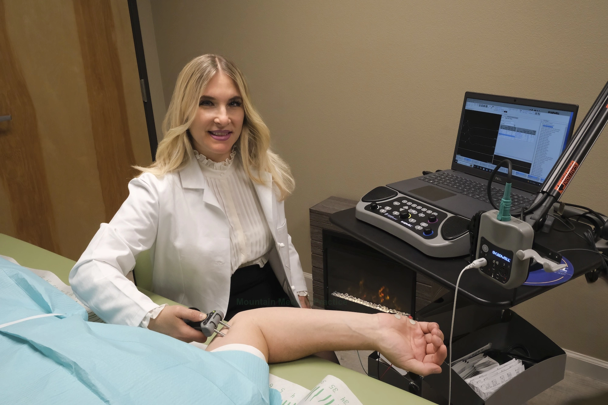 Dr. Maria Pirraglia seated at Cadwell EMG machine performing ulnar motor nerve conduction study with StimTroller device placed at supine patient’s elbow