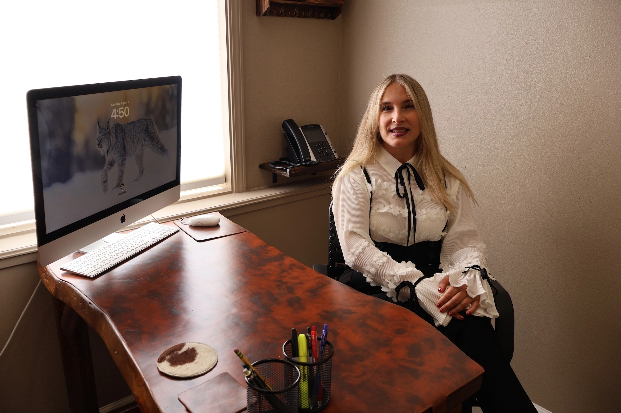 Dr. Maria Pirraglia in high-waisted Blake Suspender Pants seated at rustic style office desk with iMac desktop computer