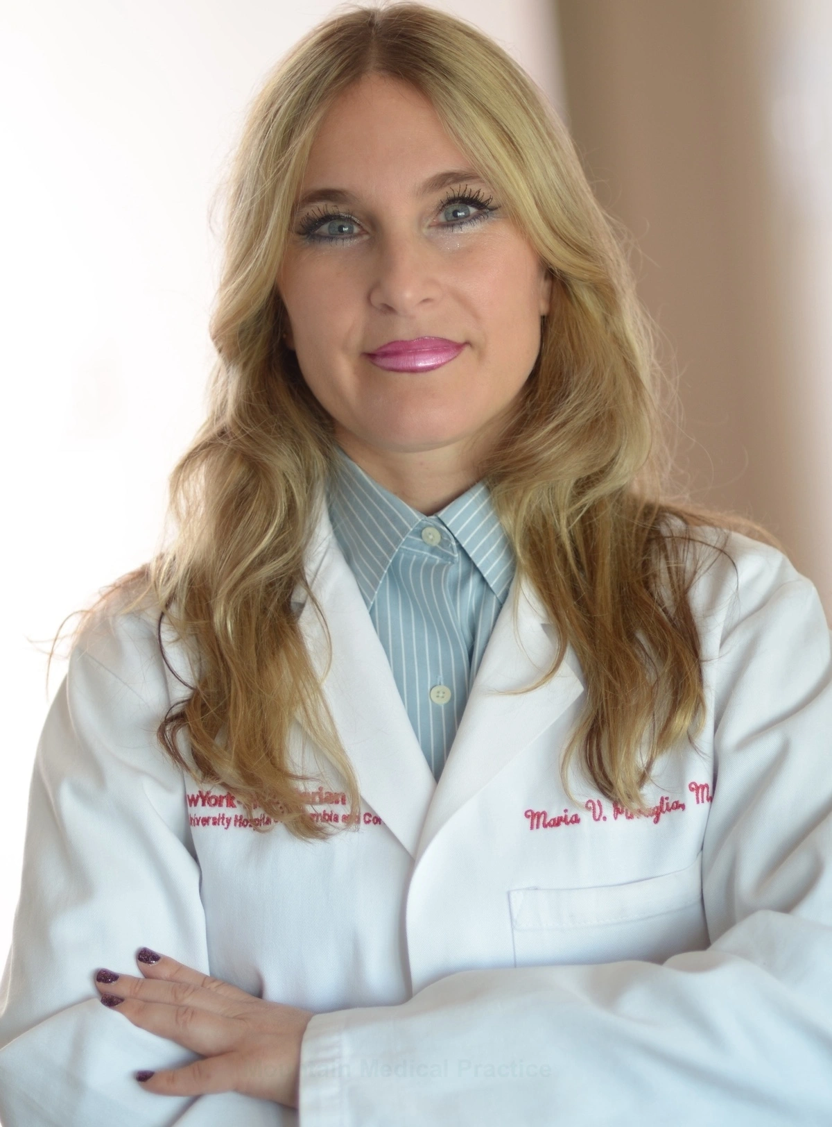 Dr. Maria Pirraglia in white lab coat and blue pinstriped blouse