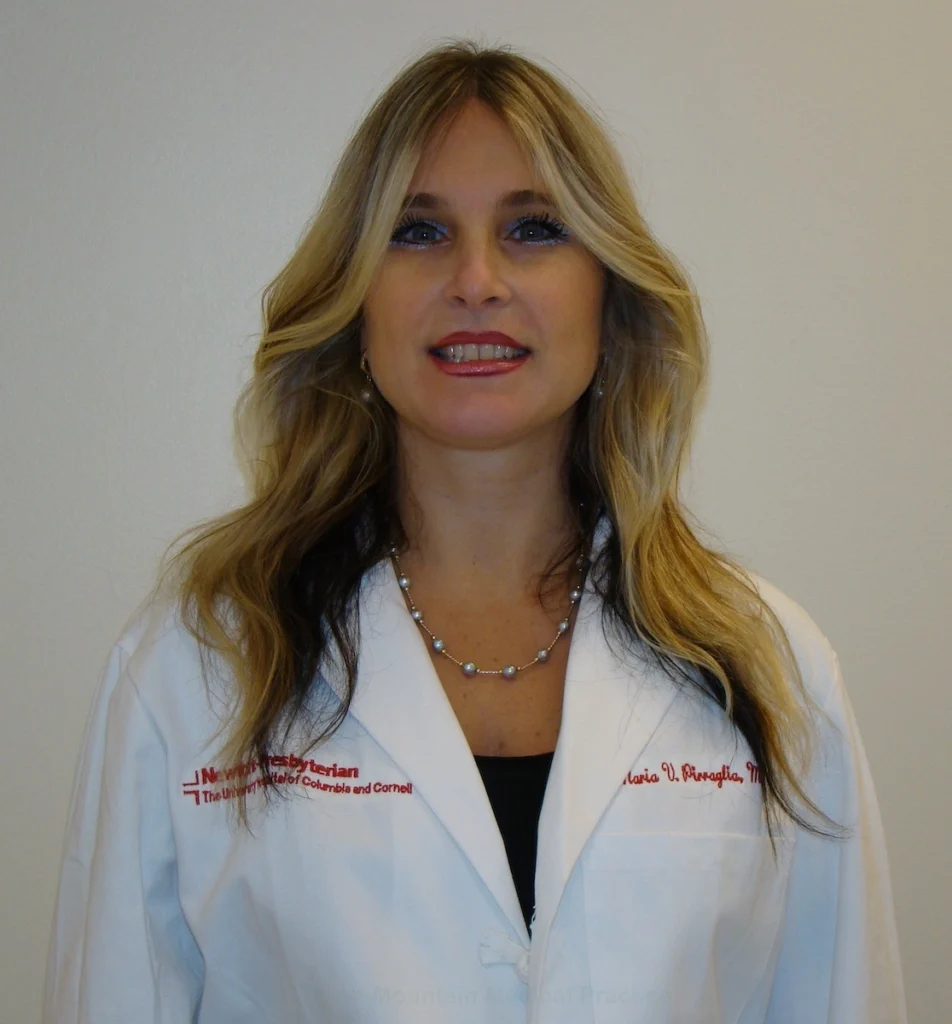 Dr. Maria Pirraglia in white lab coat and gray pearl necklace