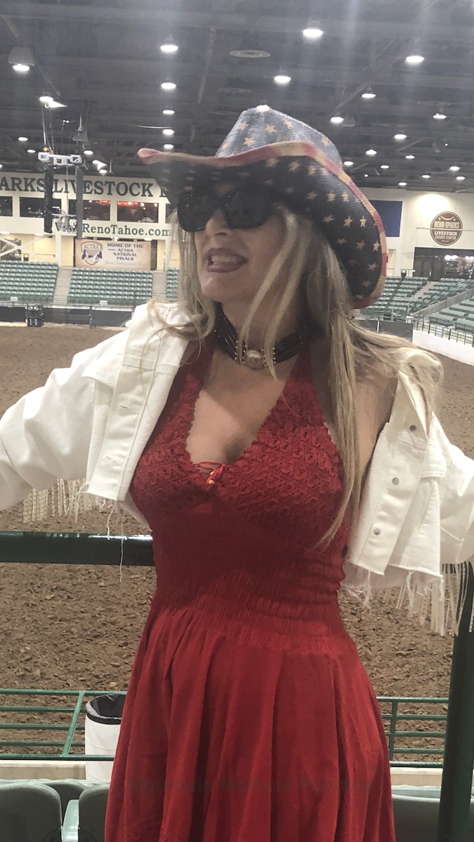 Maria Pirraglia wearing cowgirl attire, American flag western hat, red and silver bone choker, white fringe cropped jacket, and red maxi dress at Reno Rodeo