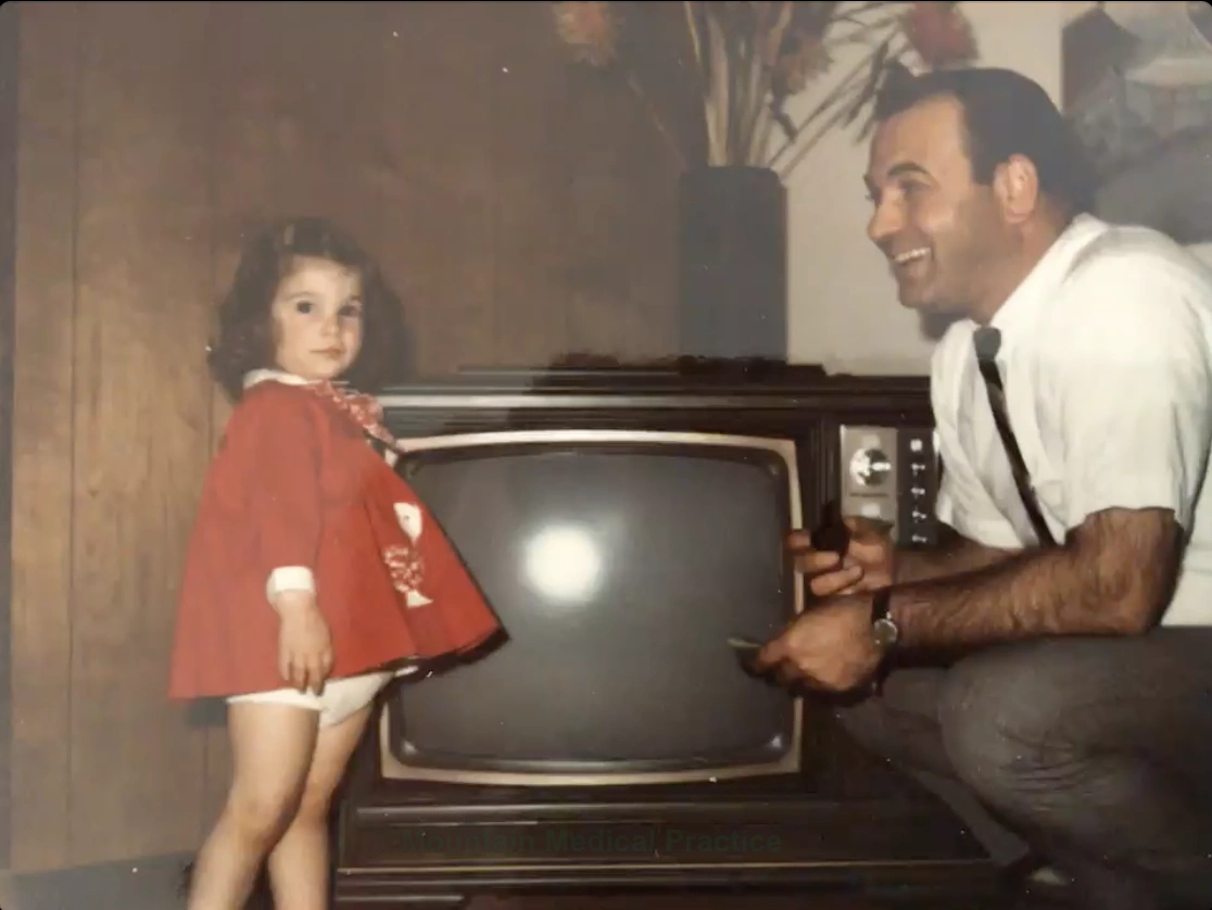 Dr. Maria Pirraglia as a toddler with Dad by the television vintage photo