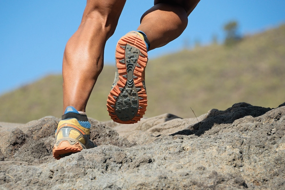 Male with well-developed calf muscles running pain-free with ease on rocky terrain