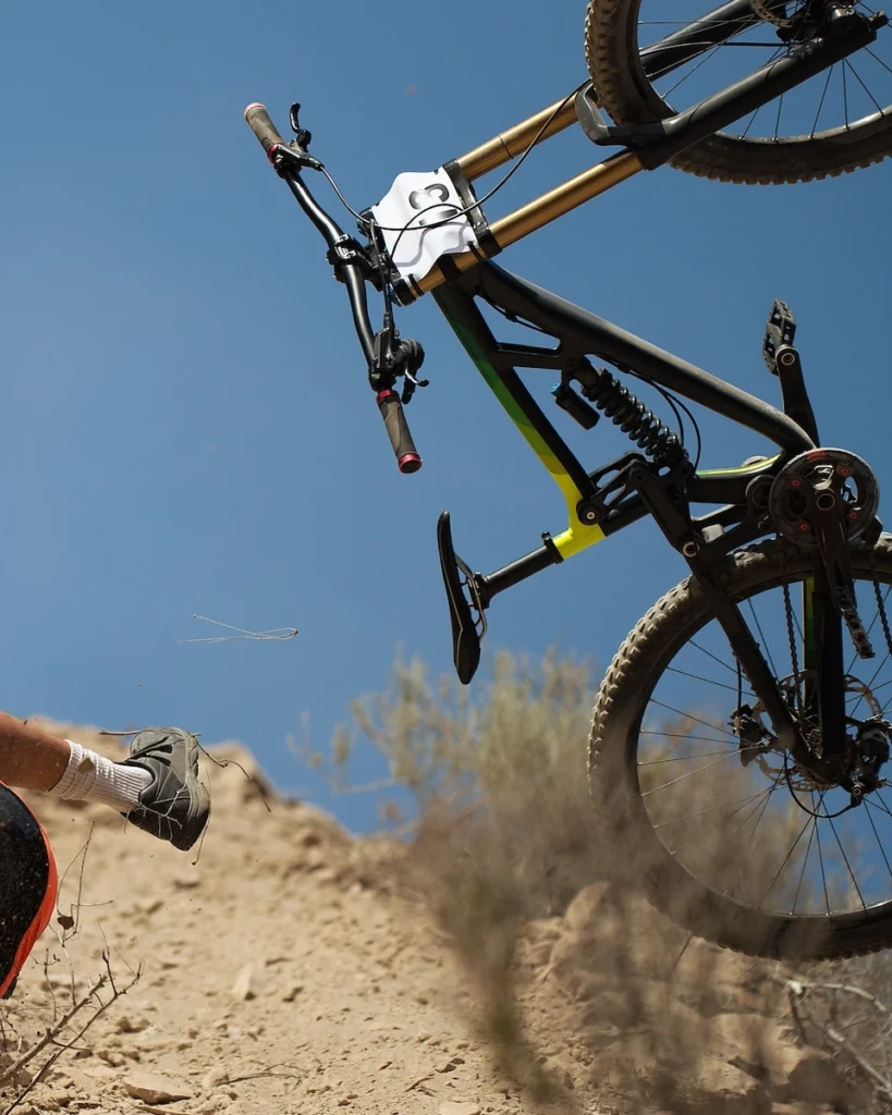 Bicycler falling off mountain bike that flips up off the dirt terrain