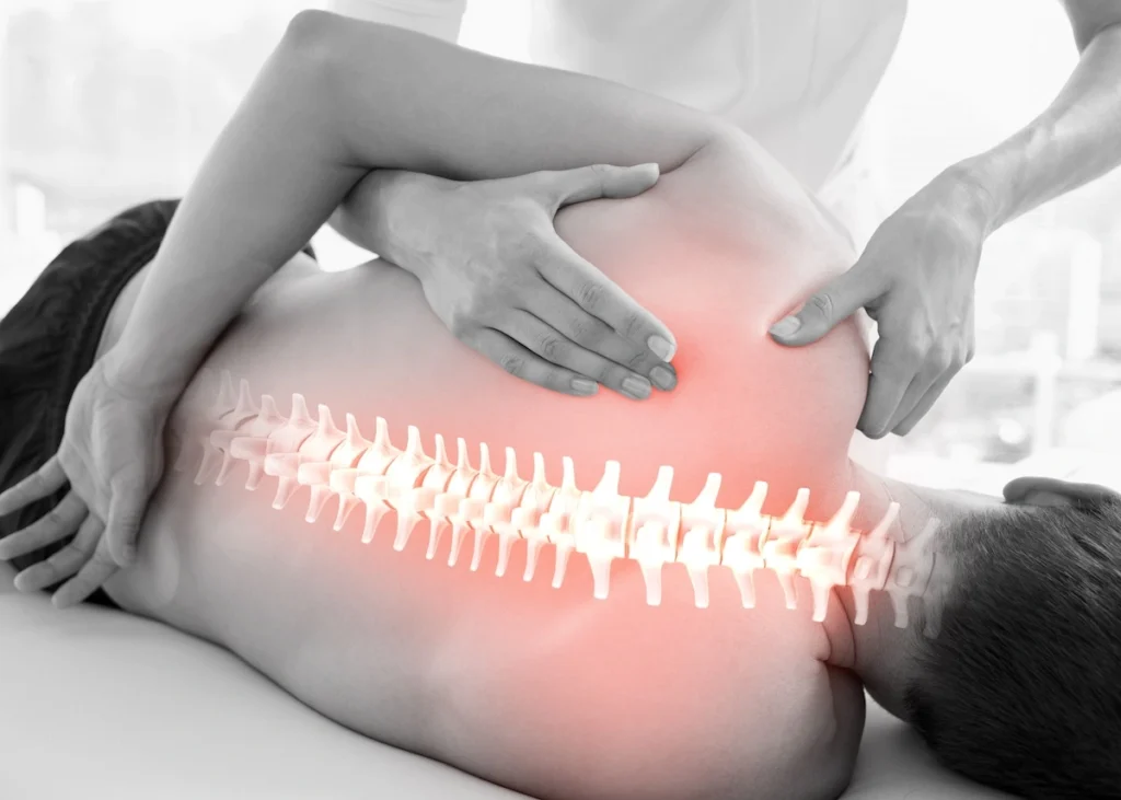Male lying sideways on exam table with inset hologram of painful spine vertebrae receiving assistance from female physical therapist