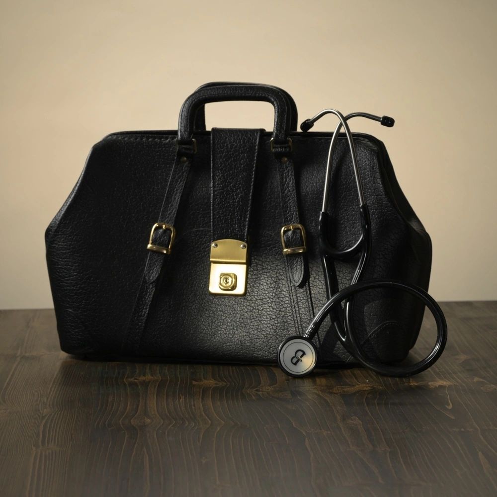 Vintage black medical doctor bag with stethoscope on tan background